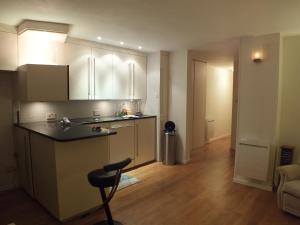 伦敦Rotherhithe apartment near park and river的厨房配有白色橱柜和黑色台面