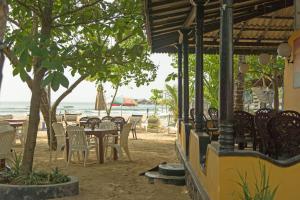 乌纳瓦图纳Hotel Dhammika的海滩上的餐厅,配有桌椅