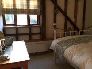 TicehurstHeartwood Barn的一间卧室设有一张床和两个窗户。