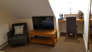 ShepshedThe Barn Courtyard的客厅配有电视、2把椅子和1张桌子