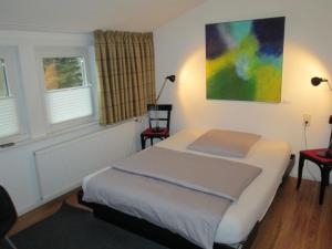 汉恩明登Hotel Schlafschön的一间卧室配有一张带两把椅子的床和一幅画