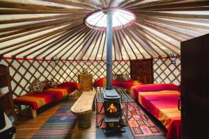 卡马森Larkhill Tipis and Yurts的圆顶帐篷配有红色的床和壁炉