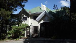 碧瑶Koinonia Retreat CenteR的白色的房子,有绿色的屋顶和门