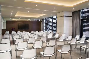 阿布扎比珍珠罗塔纳首都中心酒店的一间会议室,配有白色的椅子和屏幕
