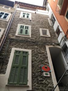 多尔切阿夸La Torre di Clo B&B的一座石头建筑,设有绿色的门窗