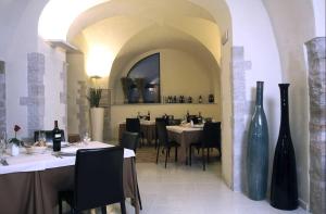 韦诺萨Hotel Orazio的餐厅设有白色桌子和黑色椅子及花瓶