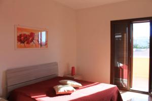 梅伦杜尼奥Residenza Santoro的一间卧室配有一张带红色床单的床和一扇窗户。