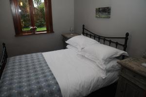 卡迪夫Ty Carreg Fach Staycation Cottage Cardiff的卧室内的一张带白色床单和枕头的床