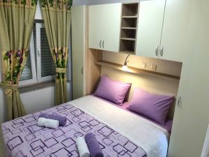 希贝尼克Apartments Galic的一间卧室配有一张带紫色枕头的床和窗户。