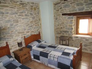 NocecoHotel rural Valtarranz的一间卧室设有两张床和石墙