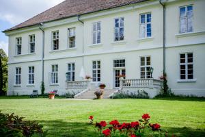 Behren-LübchinHerrenhaus Samow的院子里有红色鲜花的大白色房子