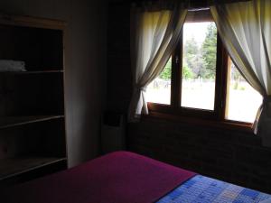 普埃洛湖Cabañas San Valentin的一间卧室设有紫色的床和窗户