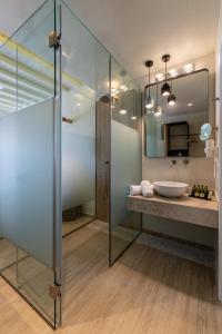 米克诺斯城海神套房酒店的一间带玻璃淋浴和水槽的浴室