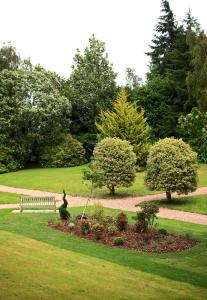 因弗内斯Inverness Lochardil House的公园里设有长凳,灌木丛和树木