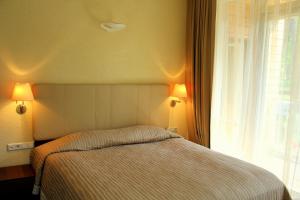 帕兰加Jūros Apartamentai的一间卧室配有一张带两盏灯的床和一扇窗户。