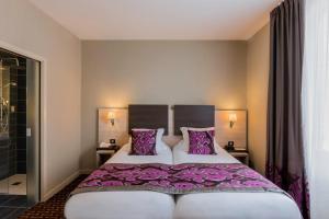 里摩日瑞切里奥贝斯特韦斯特酒店的一间卧室配有一张大床,提供紫色床单和枕头