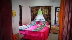Bijilo翠鸟公寓的一间卧室配有一张带粉色床单的床和一扇窗户。