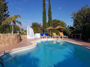 西尔韦斯Quinta Teresinha的庭院内带椅子和遮阳伞的游泳池
