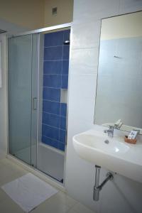 萨尔雷Ouril Hotel Agueda的一间带水槽和玻璃淋浴的浴室