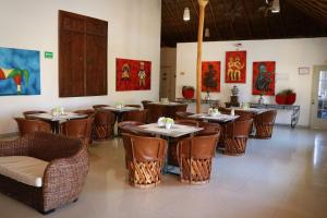 科利马扎尔科利马酒店的餐厅设有桌椅,墙上挂有绘画作品