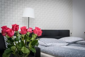 琴斯托霍瓦Apartamenty AP 1的一间卧室配有一张床和一个红色玫瑰花瓶