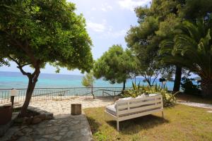 圣帕拉斯凯维Maison La Mer的坐在靠近海洋的草地上的白色长凳