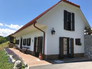 ŠtoreTourist farm Artisek的白色的房子,设有黑窗和长凳
