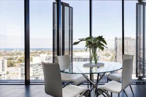 墨尔本Apartmentsouthbank的一间设有玻璃桌和白色椅子的用餐室
