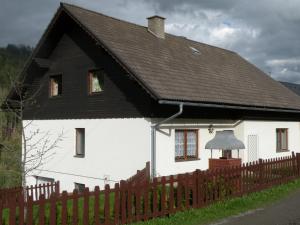 ObdachUrlaub im Zirbenland的白色的房子,有黑色的屋顶和栅栏