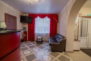 特维尔无产者酒店的客厅配有真皮座椅和红色窗帘