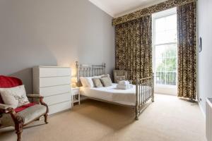 爱丁堡JOIVY Spacious 2BR Apt in New Town, Prime Location的卧室配有床、椅子和窗户。