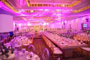 马亚圭斯马亚圭斯度假村和赌场度假酒店的宴会厅配有白色桌椅和紫色照明