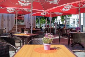 宾茨德意志旗酒店的一个带桌椅和红伞的庭院