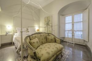科尔多瓦阿尔贝卡豪华公寓套房的一间卧室配有一张天蓬床和椅子