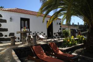 蒂哈拉费Casa Rural Los Geranios 1的一座房子,配有两把椅子和一棵棕榈树