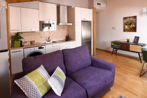 韦斯卡Arbesa Huesca的一间带紫色沙发的客厅和一间厨房