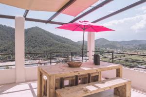 卡拉隆加Apartamentos Catharina Maria的阳台上配有带粉红色遮阳伞的桌子