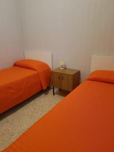 莫诺波利Villa Lilly的配有橙色床单和桌子的客房内的两张床