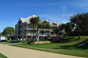黄金海岸圣地海滩度假酒店的一座大型公寓楼,前面有棕榈树