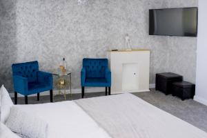 布加勒斯特Brater Luxury的一间卧室配有床、两把蓝色椅子和电视