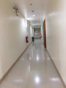 利帕Meaco Royal Hotel - Lipa的走廊设有白色墙壁和白色瓷砖地板
