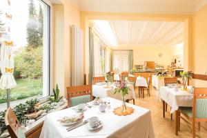 奥格斯堡Villa Arborea的餐厅设有白色的桌椅和大窗户