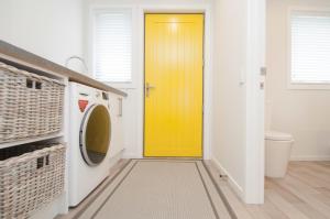 特威泽尔Luxury Rata Apartment - B的洗衣房的黄色门,配有洗衣机