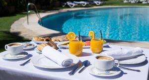 多列毛利诺斯MS特罗皮卡纳酒店的一张桌子,旁边是游泳池,摆放着食物和饮料