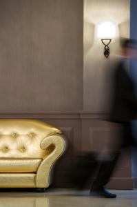 卢尔德The Originals City, Hôtel Astoria Vatican, Lourdes (Inter-Hotel)的走过带灯的金色沙发的人