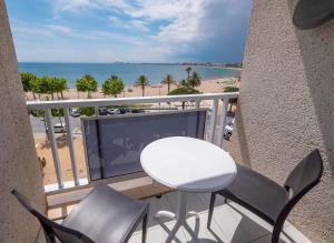 罗萨斯韦拉酒店的一个带桌椅和海滩的阳台