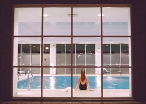 纽伯里Regency Park Hotel, Health Club & Spa的坐在游泳池中的女人透过窗户