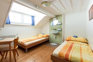 因特拉肯快乐驿站旅馆的一间卧室配有两张床、一张桌子和一个水槽