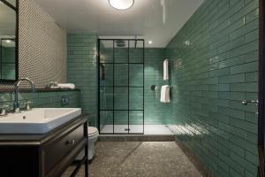 都柏林格林旅馆的浴室设有水槽和绿色瓷砖淋浴。