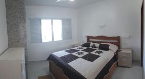 弗洛里亚诺波利斯Pousada e Camping Lagoa da Conceição的一间卧室配有一张带黑白棉被的床
